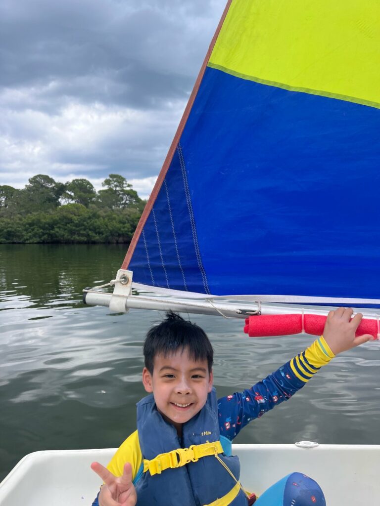 Child sailing at summer watersports camp in Florida
